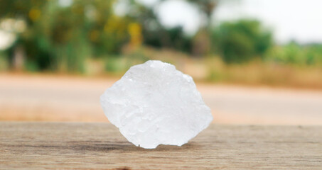 Cubes of alum on wooden surface with blur trees background. Soft and selective focus on alum.