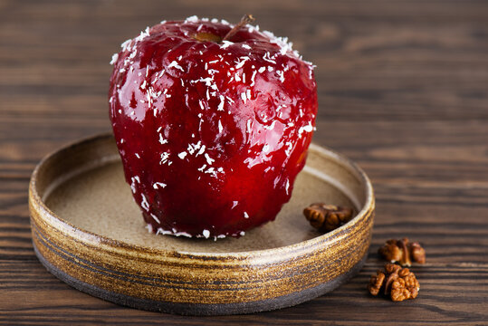 Baked apple with walnuts and honey in red glaze with coconut flakes.