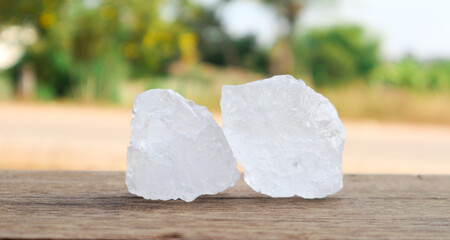 Cubes of alum on wooden surface with blur trees background. Soft and selective focus on alum.