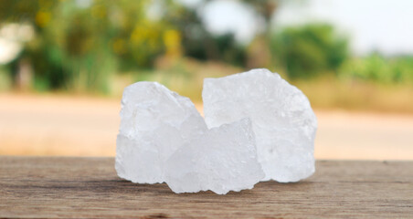 Cubes of alum on dark concrete surface and blur trees background. Soft and selective focus on alum.