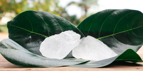 Cubes of alum on tree leaves with blur trees background. Soft and selective focus on alum.