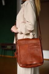 close-up photo of orange leather bag on womans shoulder