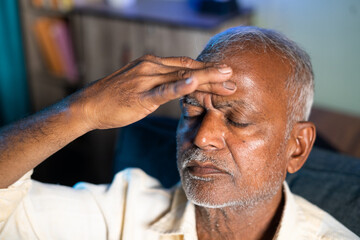 Senior man suffering from headache - concept of stress, family problems and illness during...