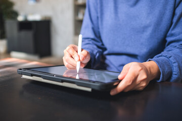 Closeup of a woman using smart pen technology for working and writing on digital tablet screen