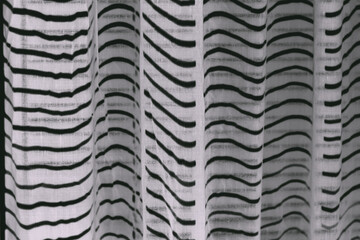 White cotton curtain with black waves as background. Cotton texture. Selective focus. Defocus.