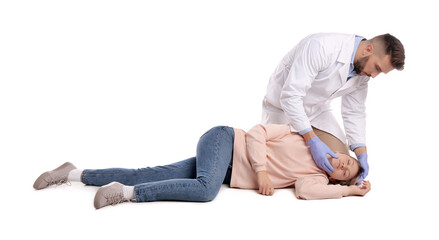 Doctor in uniform performing first aid on unconscious woman against white background - obrazy, fototapety, plakaty