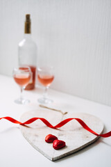 Valentines Day Festive table setting with two glasses of rose wine, red heart shape chocolate...