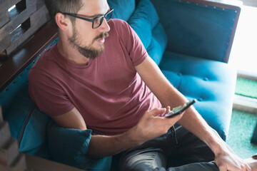 young male sitting in cafe and talk using mobile cell phone