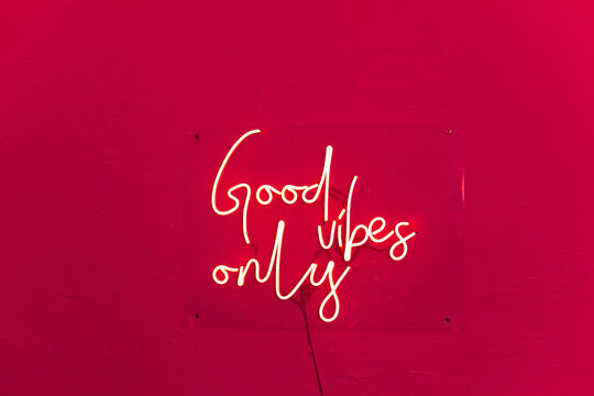 Neon words shining on the red wall. Good vibes only neon sign at the bar, cafe or at home. Viva Magenta trendy color of the year. - Powered by Adobe
