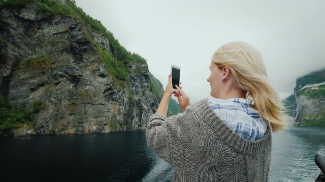A cruise ship passenger takes pictures of seagulls and beautiful scenery of the Norwegian fjord