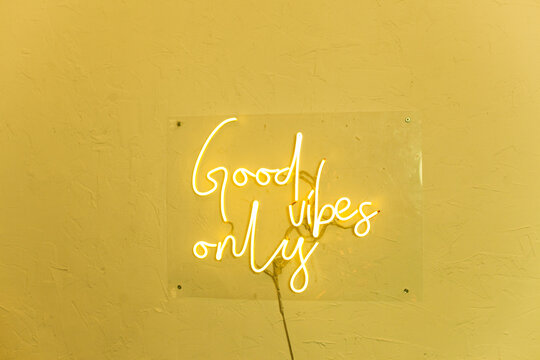 Neon words on the yellow wall. Good vibes only neon sign at the bar, cafe or at home.