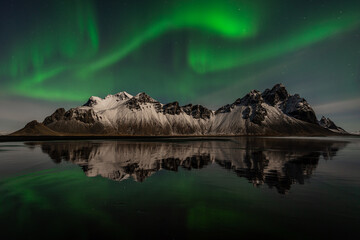 Northern lights over mountains with reflection in Iceland