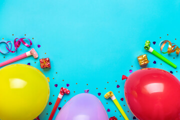 Colorful party frame with red gift box with various party confetti, balloons, streamers, pokers and decorations on blue background. Holiday card Flat lay Top view Happy Birthday party concept