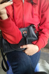 girl in red jacket holding black bag
