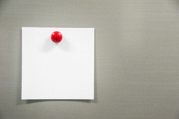 note paper with red pin on gray board, on left frame, space on right