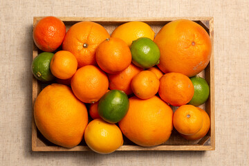Fresh citrus flat lay whole fruits - oranges, grapefruits, tangerines, lemons, lie in a wooden box
