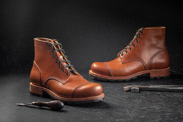 Handcrafted brown leather shoes with cobbler tools on the backgound