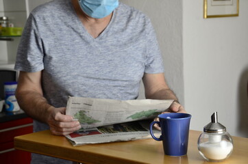 Mann mit Maske beim Zeitung lesen
