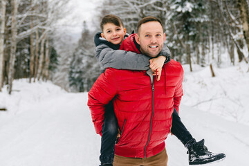 Handsome dad and his son are having fun outdoor in winter