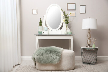 White dressing table with decor near beige wall in room