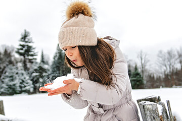 Beautiful child girl outdoors in winter. Snowing. Winter atmosphere