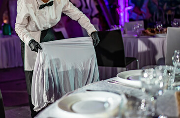 waiter puts the cover on the chair. Restaurant service. buffet or catering.

