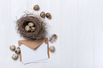 Fototapeta na wymiar Small quail eggs in bird nest and mock-up of blank white card