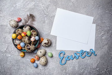 Small quail eggs, bright candies and mock-up of blank white card for Easter day