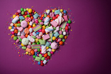Bright sweet heart of multicolored dragee, candies, lollipops, marshmallows