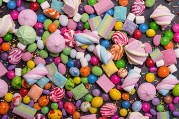 Bright background of sweet multicolored dragee, candies, lollipops, marshmallows