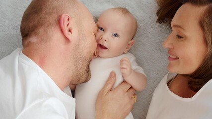 Happy parents with his newborn baby, top view. Happy family. Healthy newborn baby with mom and dad. Close up Faces of the mother, father and infant baby. Cute Infant boy and parents.