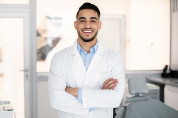 Fototapeta premium Stomatologic Services. Portrait Of Smiling Arab Dentist Doctor In Uniform