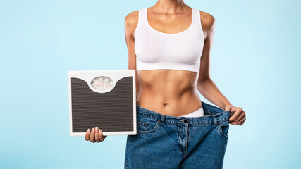 Woman Holding Scales Pulling Her Old Large Jeans