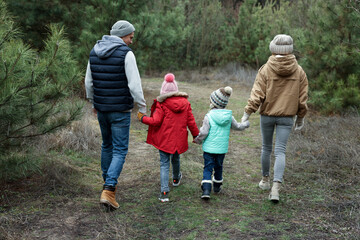 Happy family spending time together in forest, back view