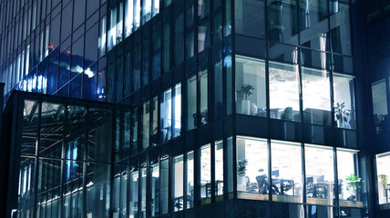 Amazing night cityscape. Office building at night, building facade with glass and lights. View with illuminated modern skyscraper. Scenic glowing windows of skyscrapers at evening. 