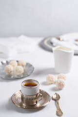 Una taza de té clásico con dulces chocolates blancos cubiertos de coco en el cuadro blanco	