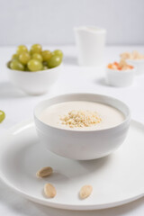 Crema de almendras, sopa fría española. Ajo blanco de Málaga con almendras y uvas en un recipiente blanco sobre una mesa blanca	