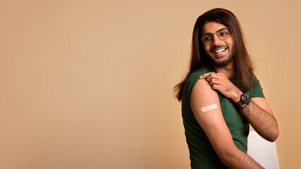 Healthy middle-eastern man showing medical band, got vaccinated