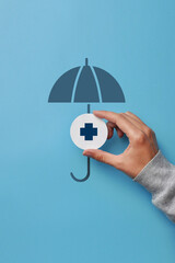 A medical cross and an umbrella over it. Symbol of health insurance and life protection - obrazy, fototapety, plakaty