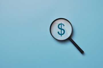 the silhouette of a dollar and a magnifying glass aimed at it. Money Search Symbol