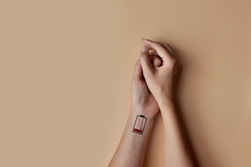 Hands with the image of a discharged battery on it. A symbol of lack of energy and fatigue in a...