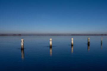 Fototapeta na wymiar A view of empty docks in the winter. Blue water and a clear blue sky