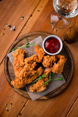 Fried crispy chicken nuggets with ketchup on board