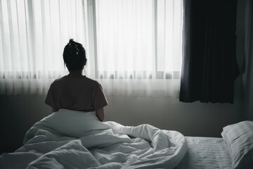 Depressed asian woman has sad and lonely feel sitting on the bed in the morning.