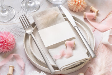 Wedding Table place with a card over napkin near flowers, silk ribbons and feathers, mockup