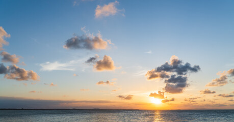 Sunset sky clouds over sea in the evening with orange sunlight golden hour, dusk sky 