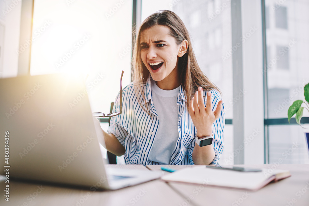 Poster angry stressed female freelancer irritated with bad internet connection sitting at desktop with netb