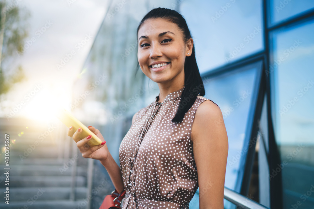 Poster portrait of charming millennial blogger smiling at camera while posing at city urbanity,happy asian 