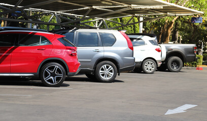 Closeup of red sedan car with other cars parking in outdoor parking area in bright sunny day. 