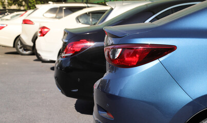 Closeup of blue sedan car with other cars parking in outdoor parking area in bright sunny day. 